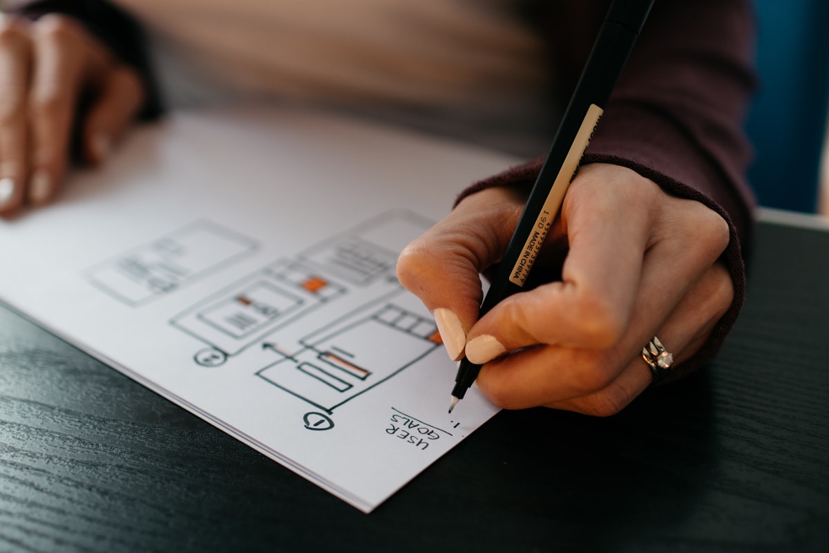 Hand sketching mobile app wireframes and user goals on paper — planning app development